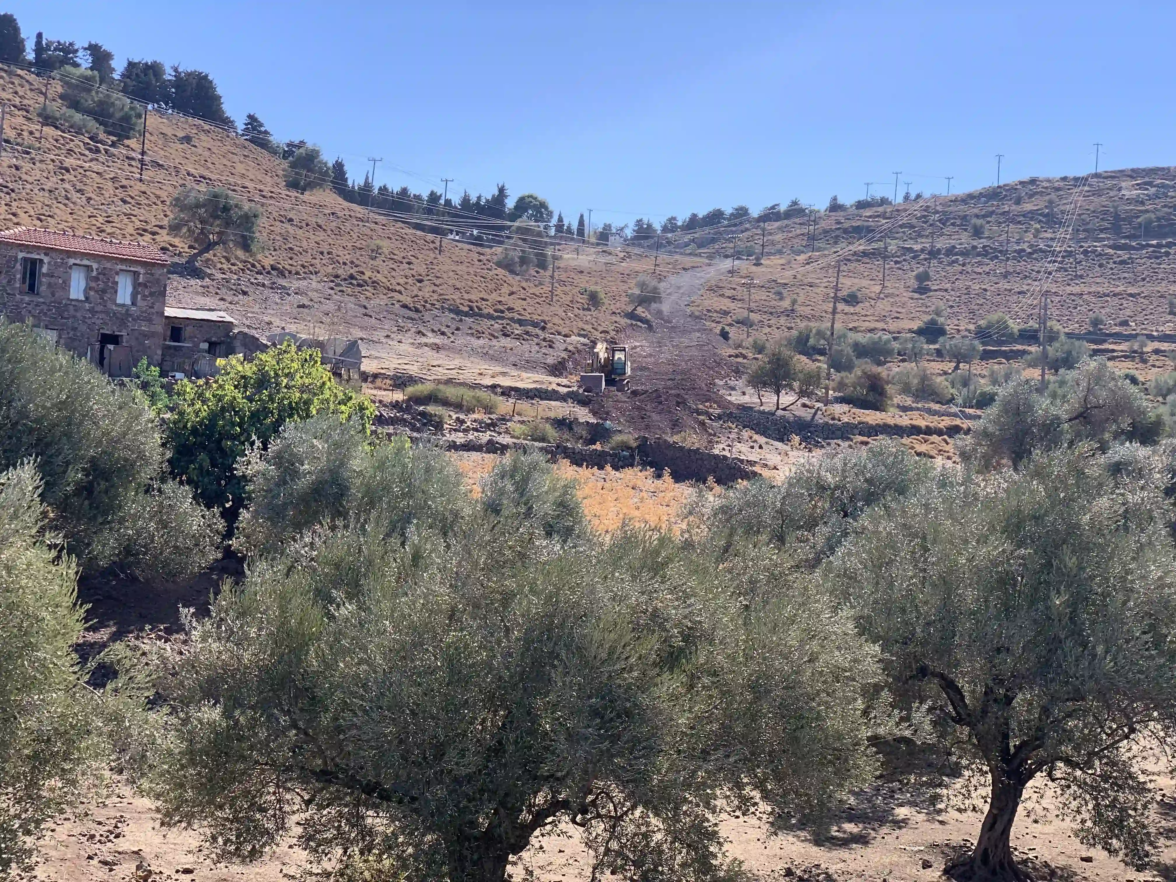 Απεικόνιση εργασίας εκσκαφών με μηχάνημα για τοποθέτηση σωλήνων ύδρευσης στην περιοχή της ΔΕΗ σε λόφο.